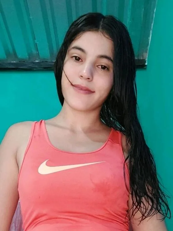 Woman with long dark hair in a coral tank top